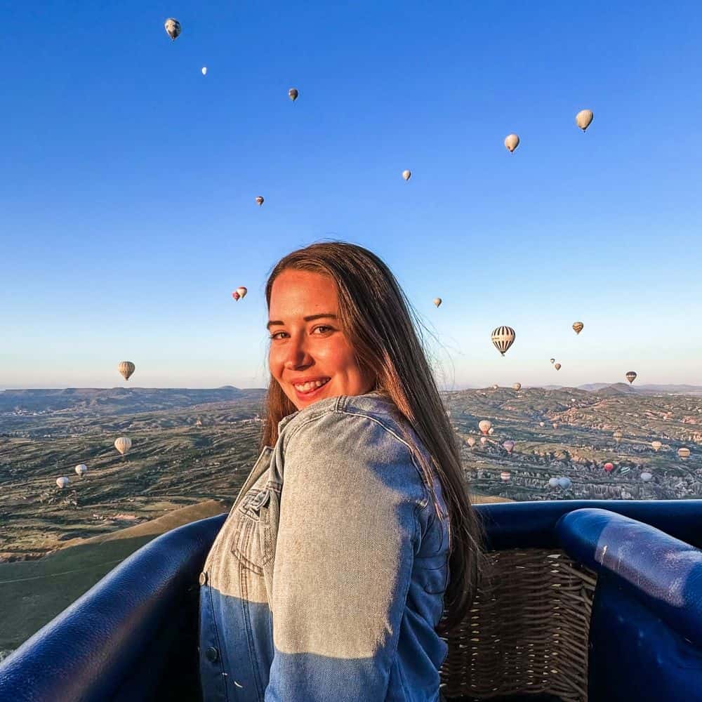 Me in front of a bright blue sky filled with hot air balloons